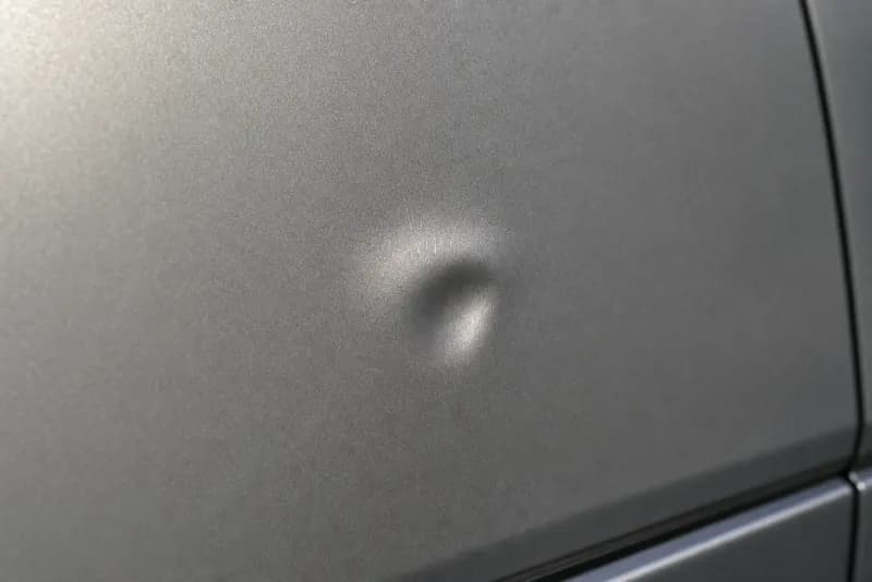 Close-up photograph of prior damage on a car panel